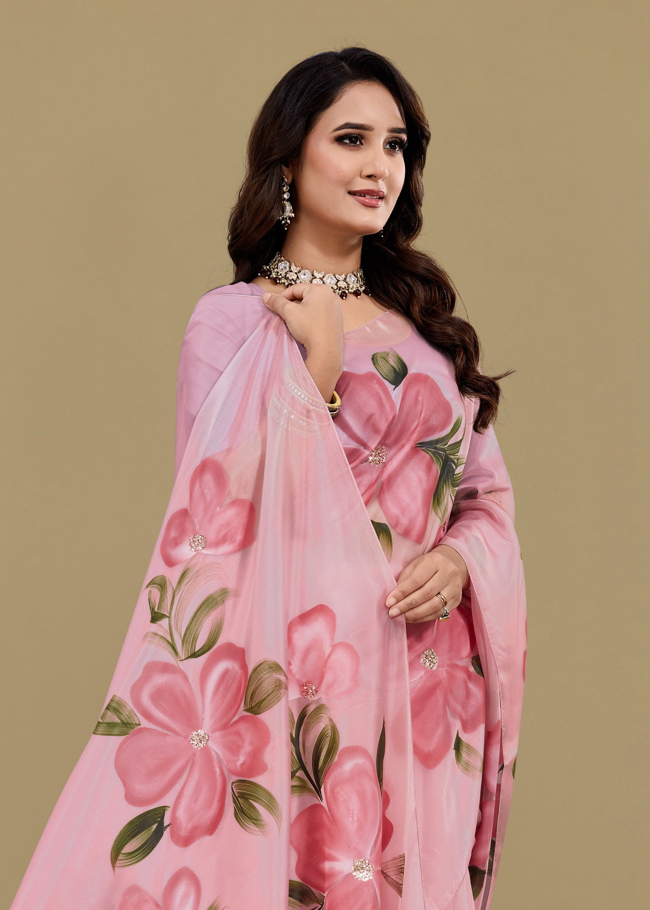 Woman wearing a pink floral saree against a beige background